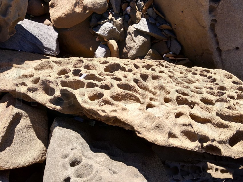 Piedras con agujeros de erosión rocosa en la playa de España