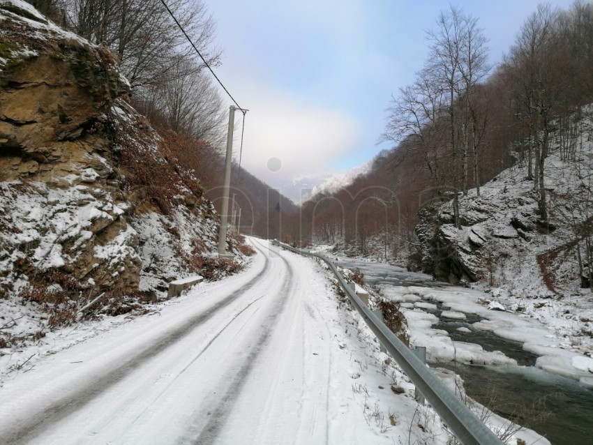 El paisaje de invierno camino con nieve y río congelado